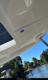 Close-up of a center console boat's exterior with a blue g4 light, water and trees in the background.